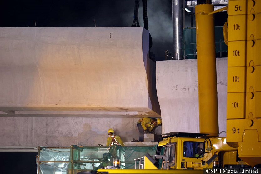 A worker grinding the surface of a supporting column to ensure it fits with an installed segment of the bridge.