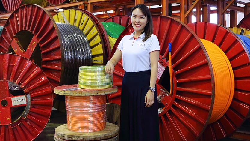 Pearl Yu, director of marketing and human resources at Keystone Cable, poses with rolls of cables